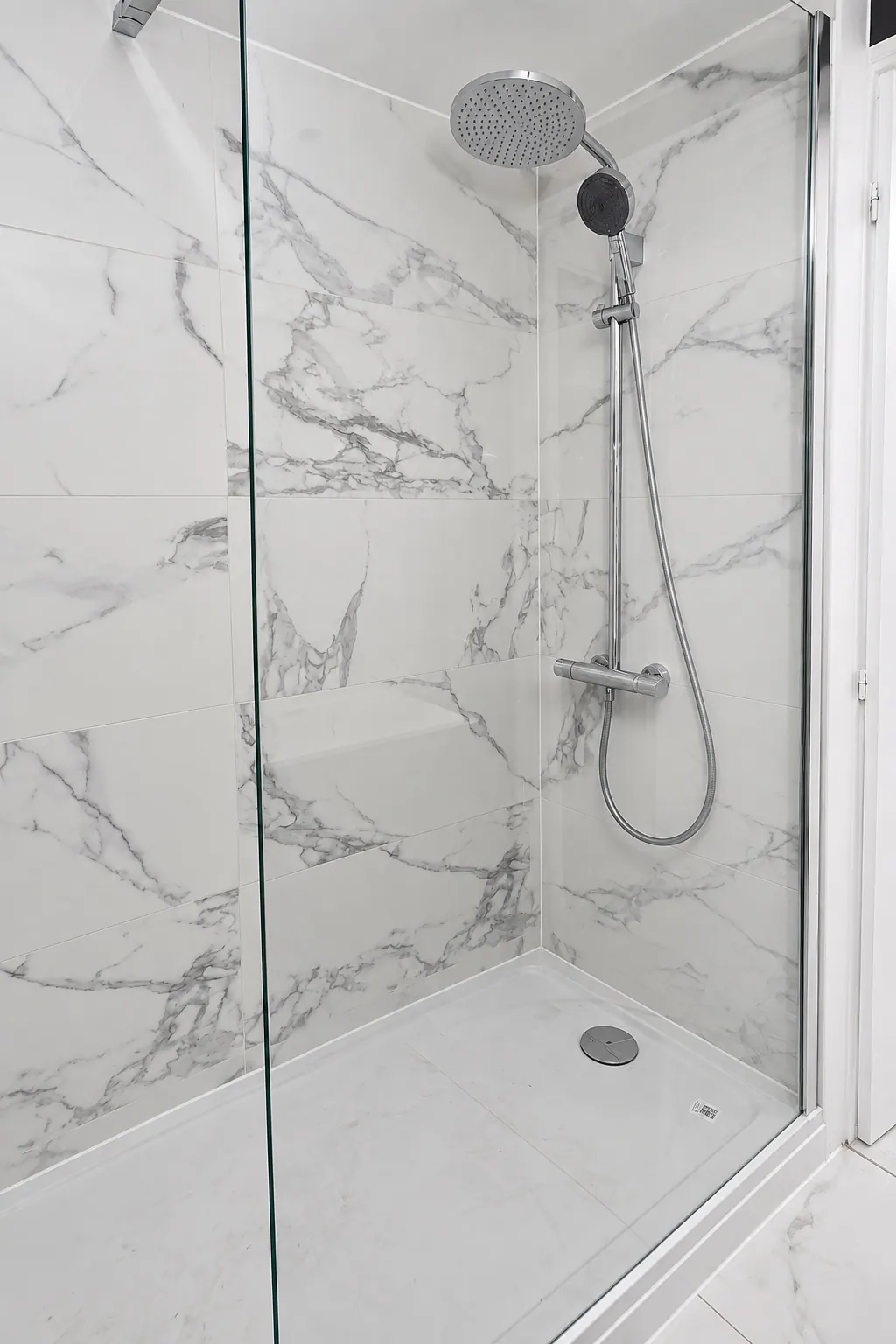 Douche à l’italienne avec colonne de douche et murs effet marbre