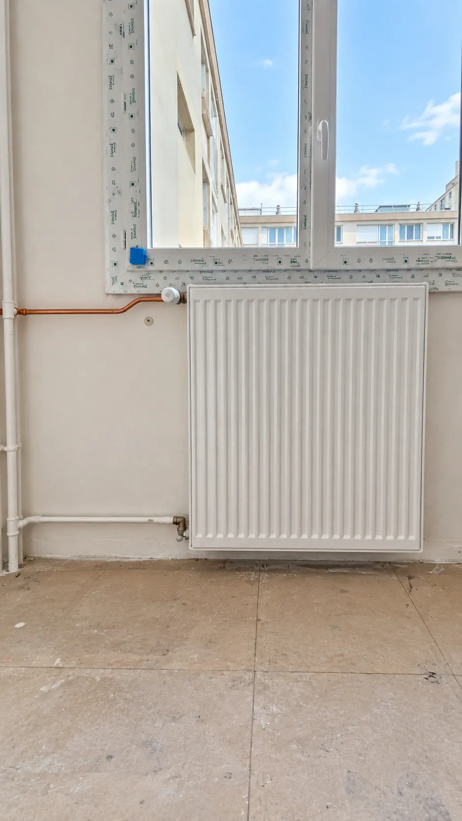 Radiateur posé sous une fenêtre, raccordement cuivre, en cours de chantier